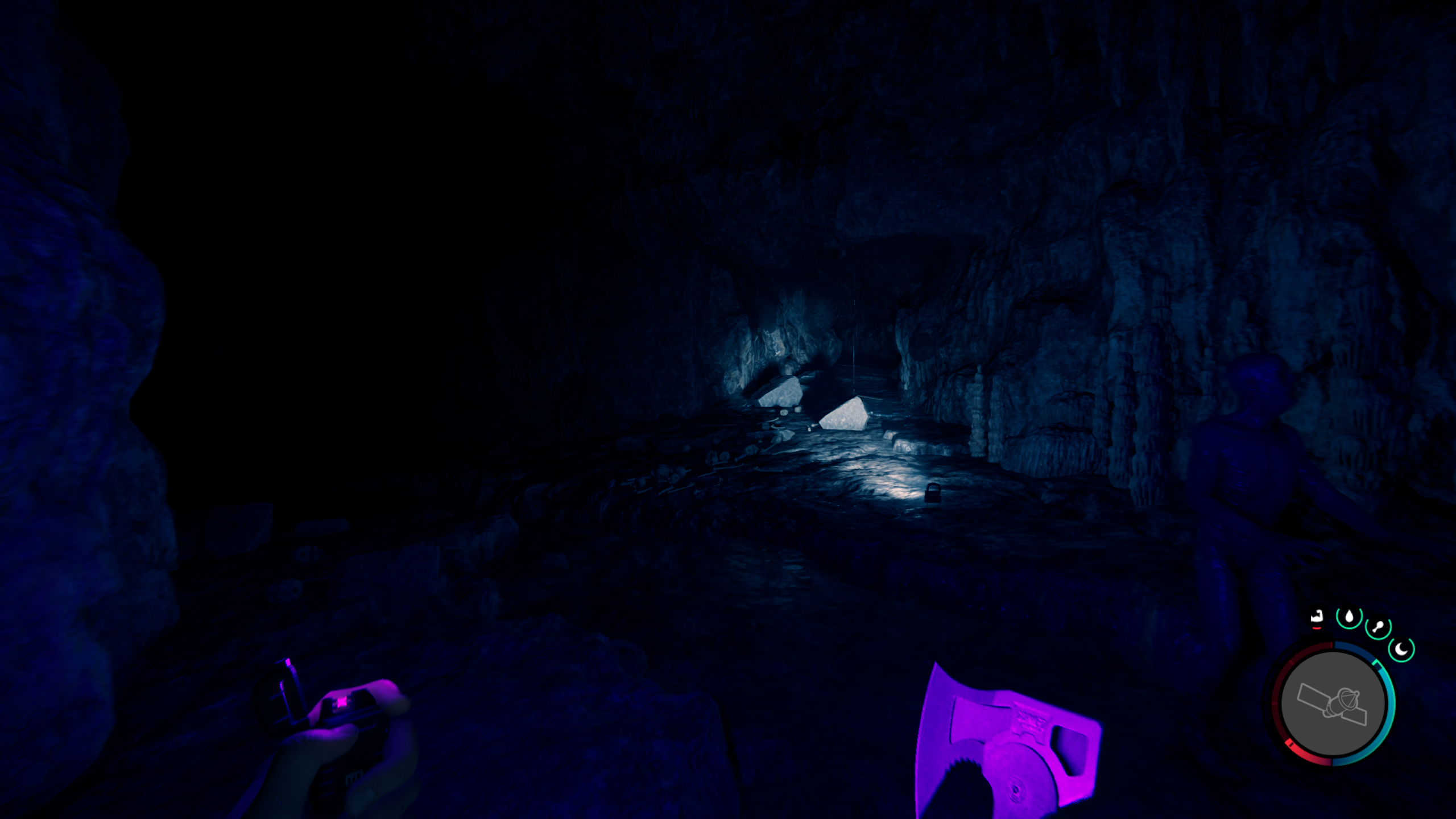 Sons of the Forest - a room in the rebreather cave with a light shining to the right but a dark path to the left.