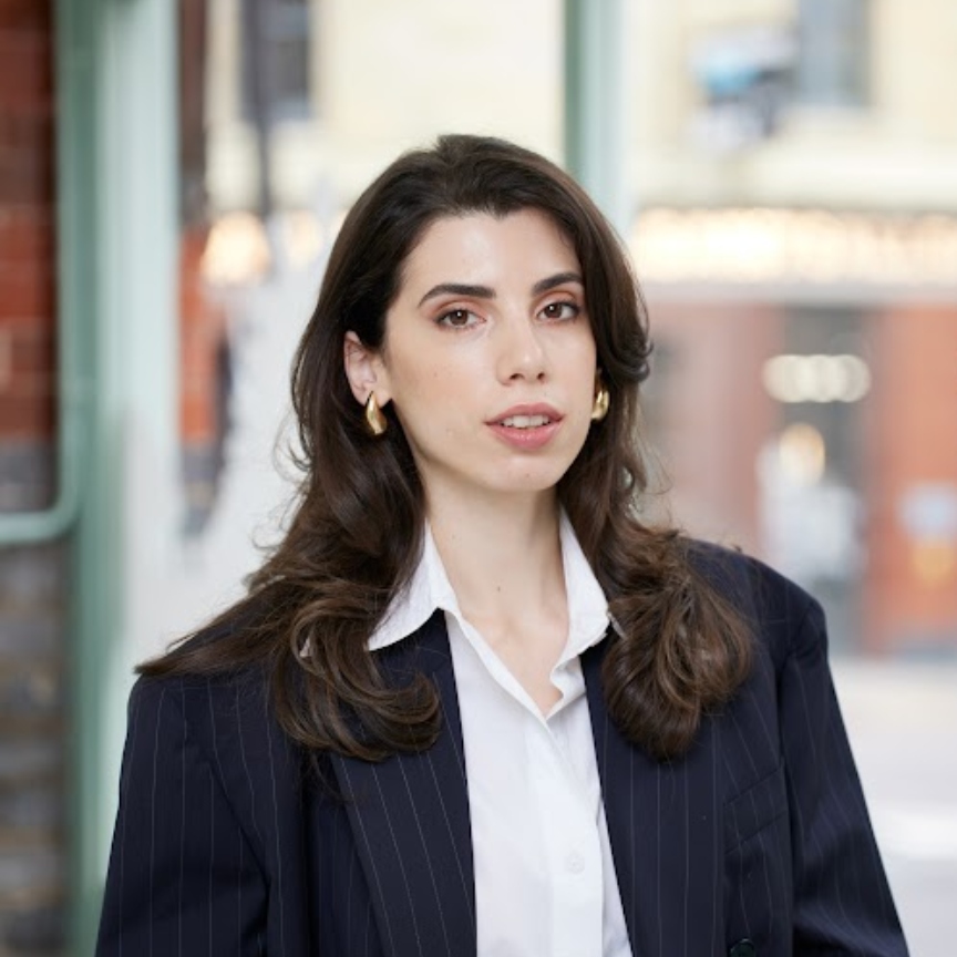 a white woman with dark hair in a black jacket and white shirt