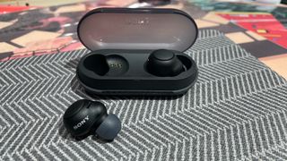 One Sony WF-C500 wireless earbud in and one out of its charging case