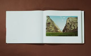 The image inside a book features a lush green grass landscape with canyon rocks on either side.