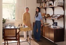 two women standing in a white room with dark wood furniture and modern decor