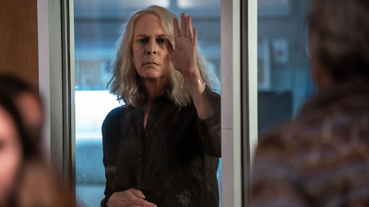 Laurie Strode (Jamie Lee Curtis) puts her hand on a plane of glass in Halloween Kills