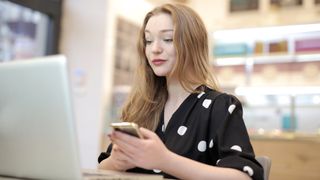 Best website hosting services: young woman using phone and laptop