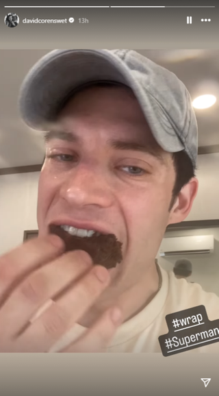 David Corenswet craming a piece of cake in his mouth