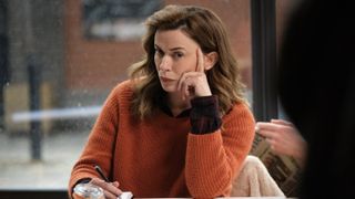 Eve Myles in an orange jumper as Jeanette Kilburn sits at a table in The Crow Girl