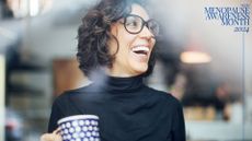 Woman holding up cup of coffee, wearing glasses, laughing and smiling, representing what happens when you come off HRT