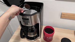 scoping ground coffee into the Mr. Coffee 12 Cup Programmable Coffee Maker