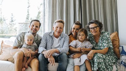 A multigenerational family sits on a couch, including grandparents, parents and children.
