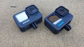 GoPro HERO 10 Black and HERO 9 Black with bunny ears extended, lying on a beach