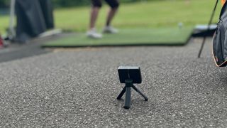 The Garmin R10 launch monitor in use at a driving range