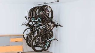 A group of different bike types, including road bikes, mountain bikes and children's bikes, are suspended from a rail in the ceiling