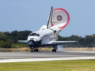 With its drag chute unfurled, space shuttle Discovery rolls down Runway 15 at the Shuttle Landing Facility at NASA's Kennedy Space Center in Florida.