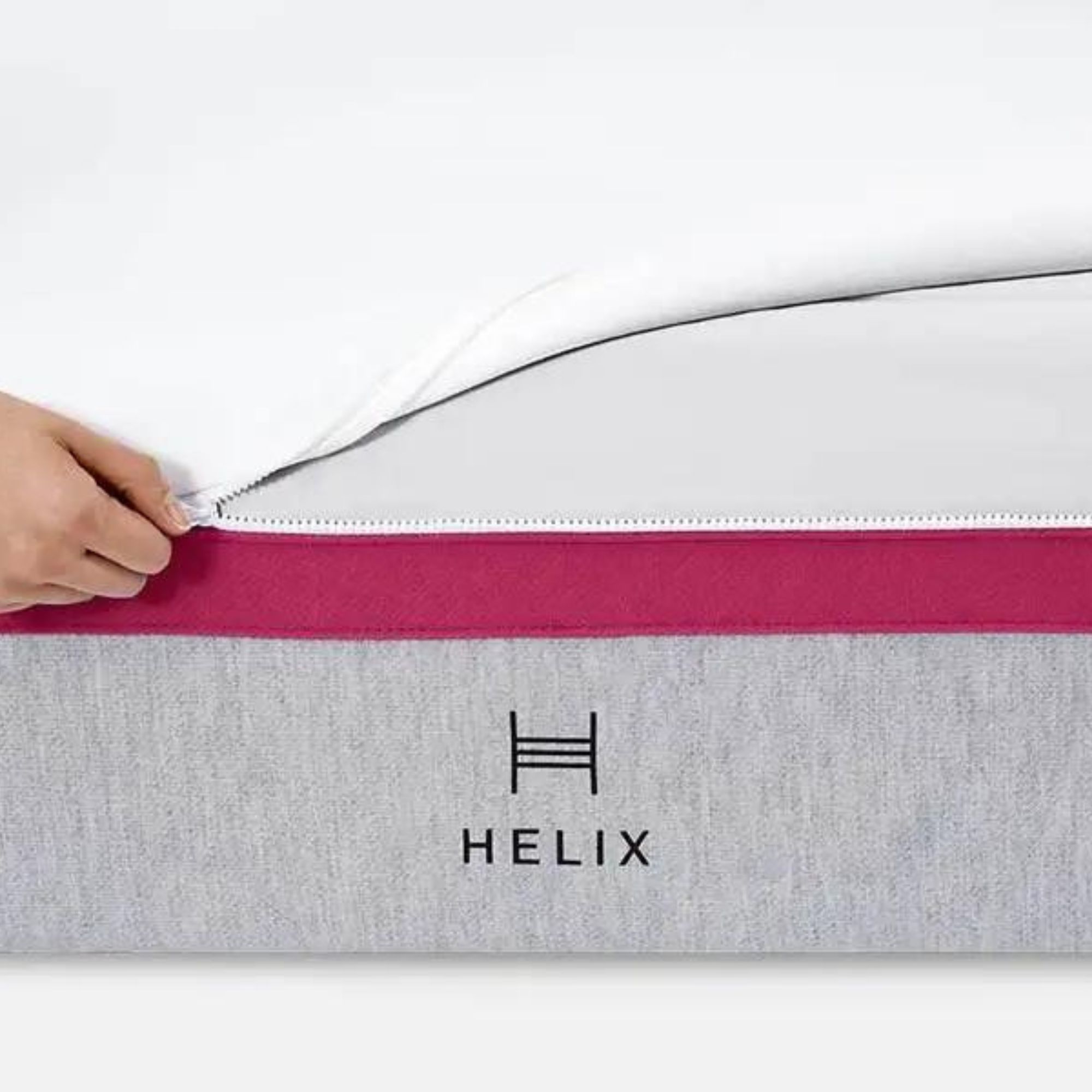 A hand zipping the cover of the Helix Dusk Mattress.