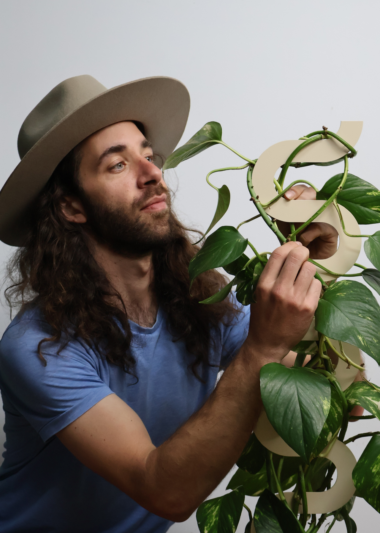 A headshot of Mike Sullivan, founder of Secateur Me Baby, adjusting the vines of a houseplant