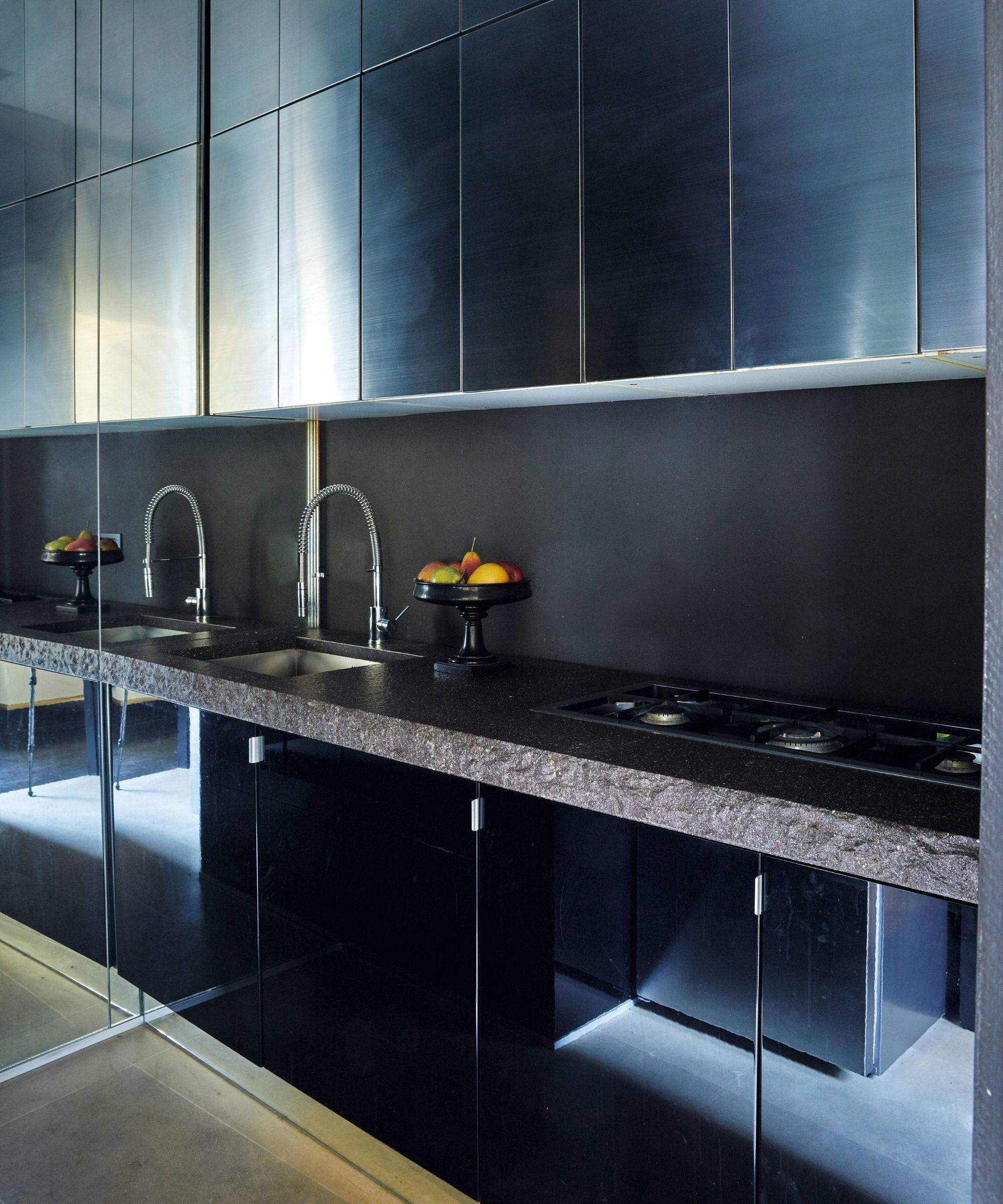 a stainless steel kitchen with stone countertop and sleek flat front cabinetry