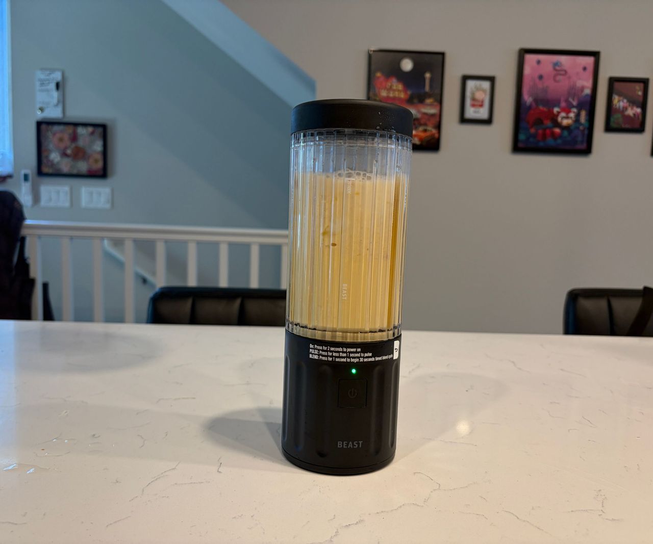 A yellow smoothie inside a small portable blender with a black base and lid.