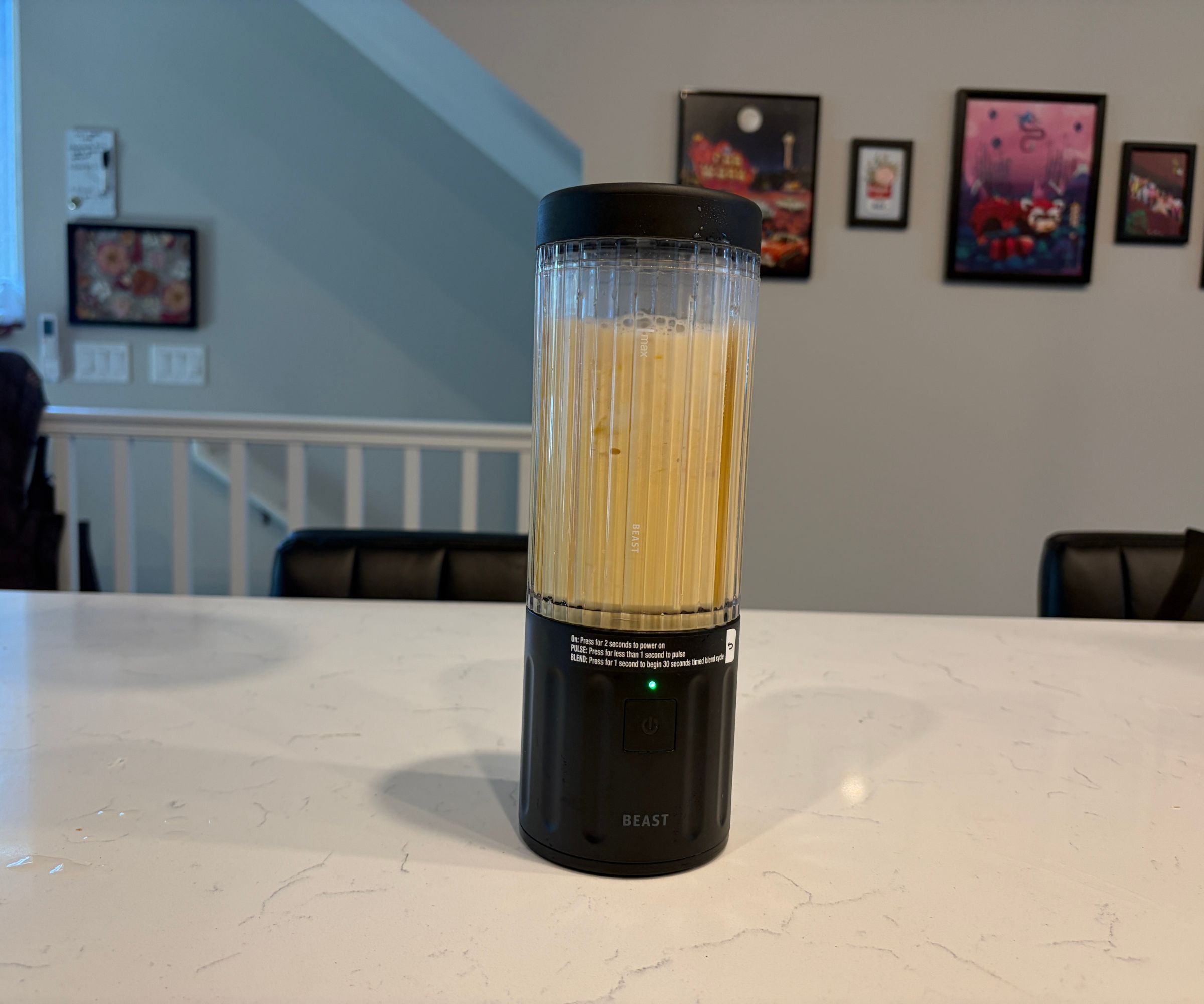 A yellow smoothie inside a small portable blender with a black base and lid.
