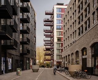 The Brentford Project showing brick residential blocks with large balconies and warehouse inspired streets and public spaces that step down to the water