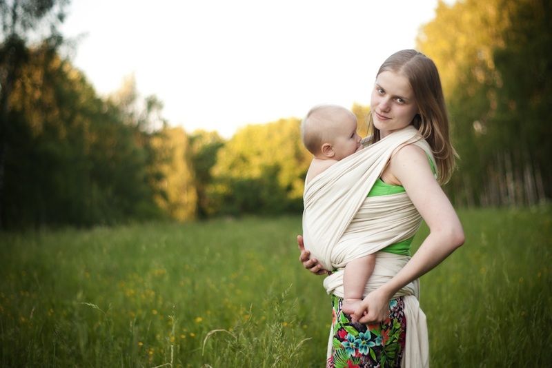 An attachment mother wearing her baby in a sling.