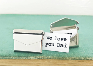A pair or silver cufflinks shaped as envelopes with little paper notes saying 'we love you Dad'.