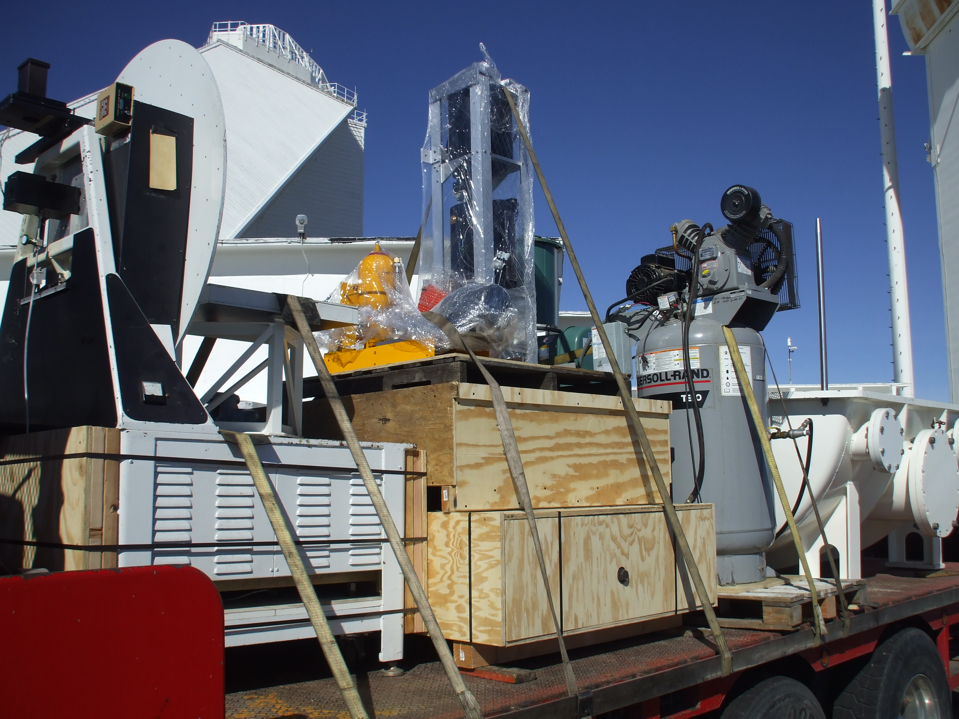 Components are placed on a flatbed trailer for the trip off Kitt Peak. All critical optics and electronics were shrink-wrapped and went down in a covered semi. Everything will be transferred to an enclosed trailer for the cross-country trip. In the backgr