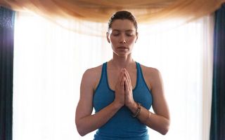 Jessica Biel meditating, wearing blue workout vest