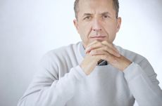Portrait of middle aged serious businessman sitting with hands