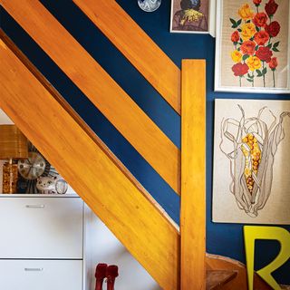 blue hallway with retro wooden staircase and artwork
