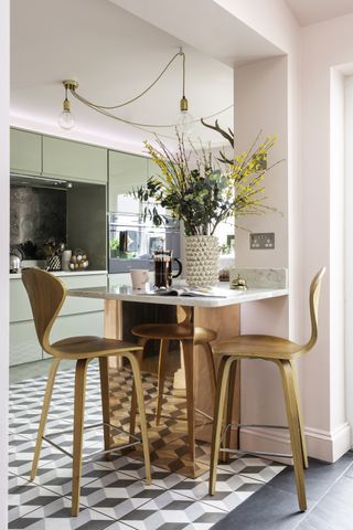 A bar area at the end of a run of kitchen units complete with copper coating and wooden bar stools