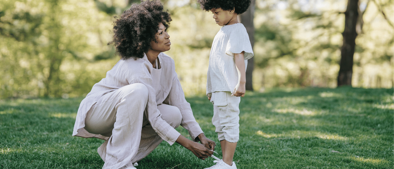 Image of woman tying a child&#039;s shoelace