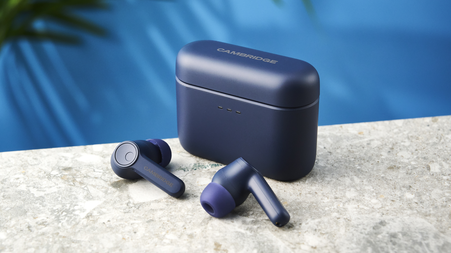 the cambridge audio a100 se earbuds on a blue tom's guide background with a stone-coloured table underneath