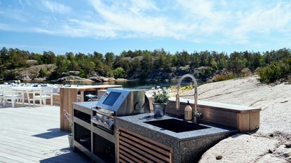 roost episode 4 - outdoor kitchen by rocks at a beach with white outdoor furniture - Pic-credit-Lundhs