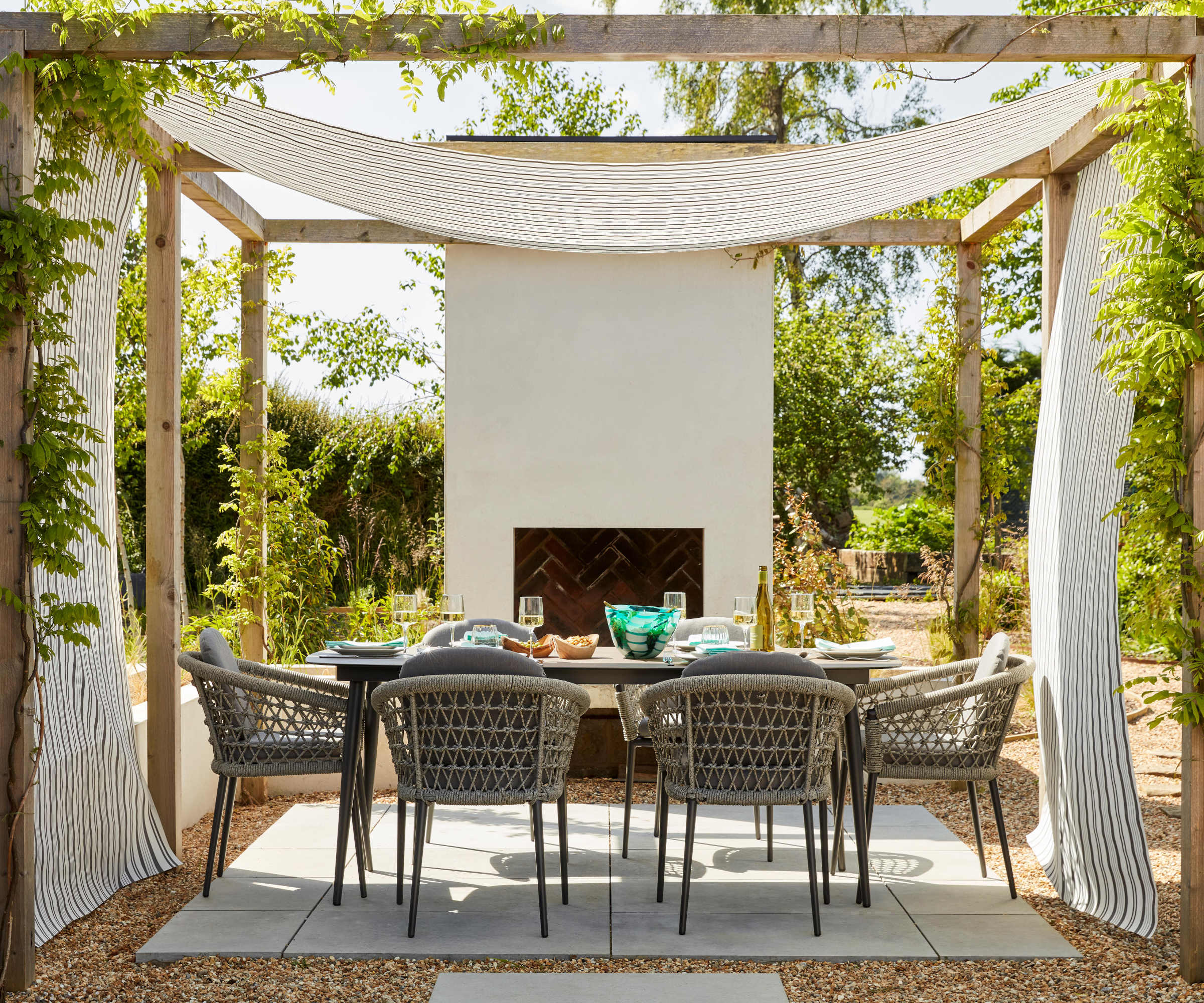 wooden pergola with fabric draped across the roof and seating area below