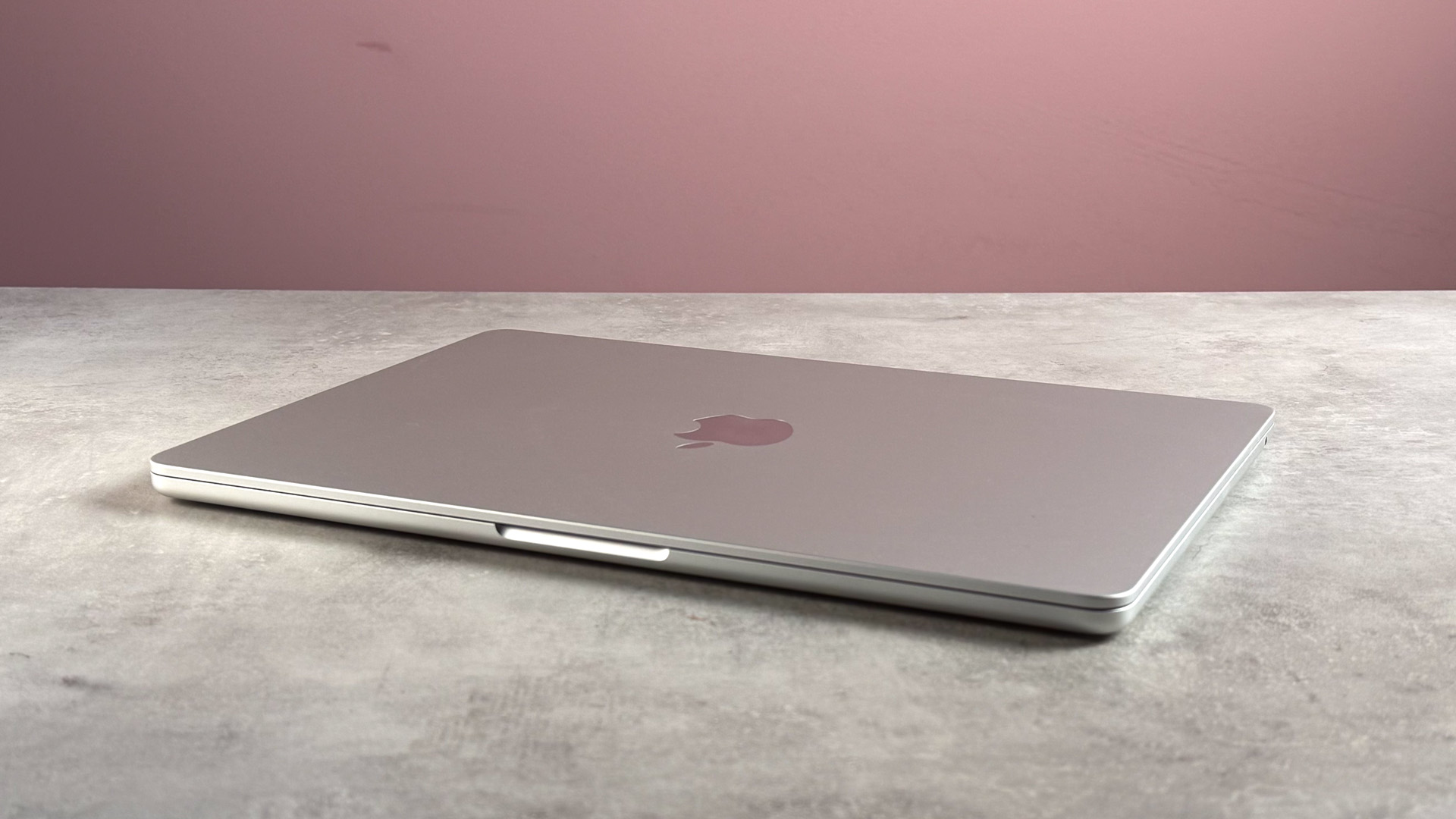 The MacBook Air M5 closed on on a stone effect surface in front of a pink background