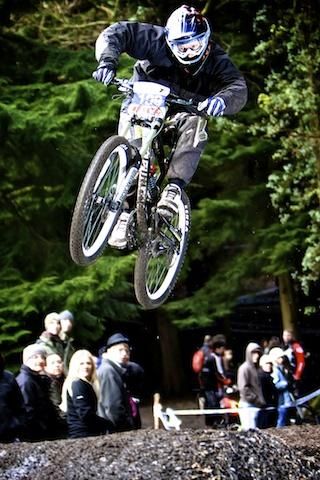 A racer speeds through the air past spectators