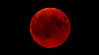 a blood red moon in a black night sky