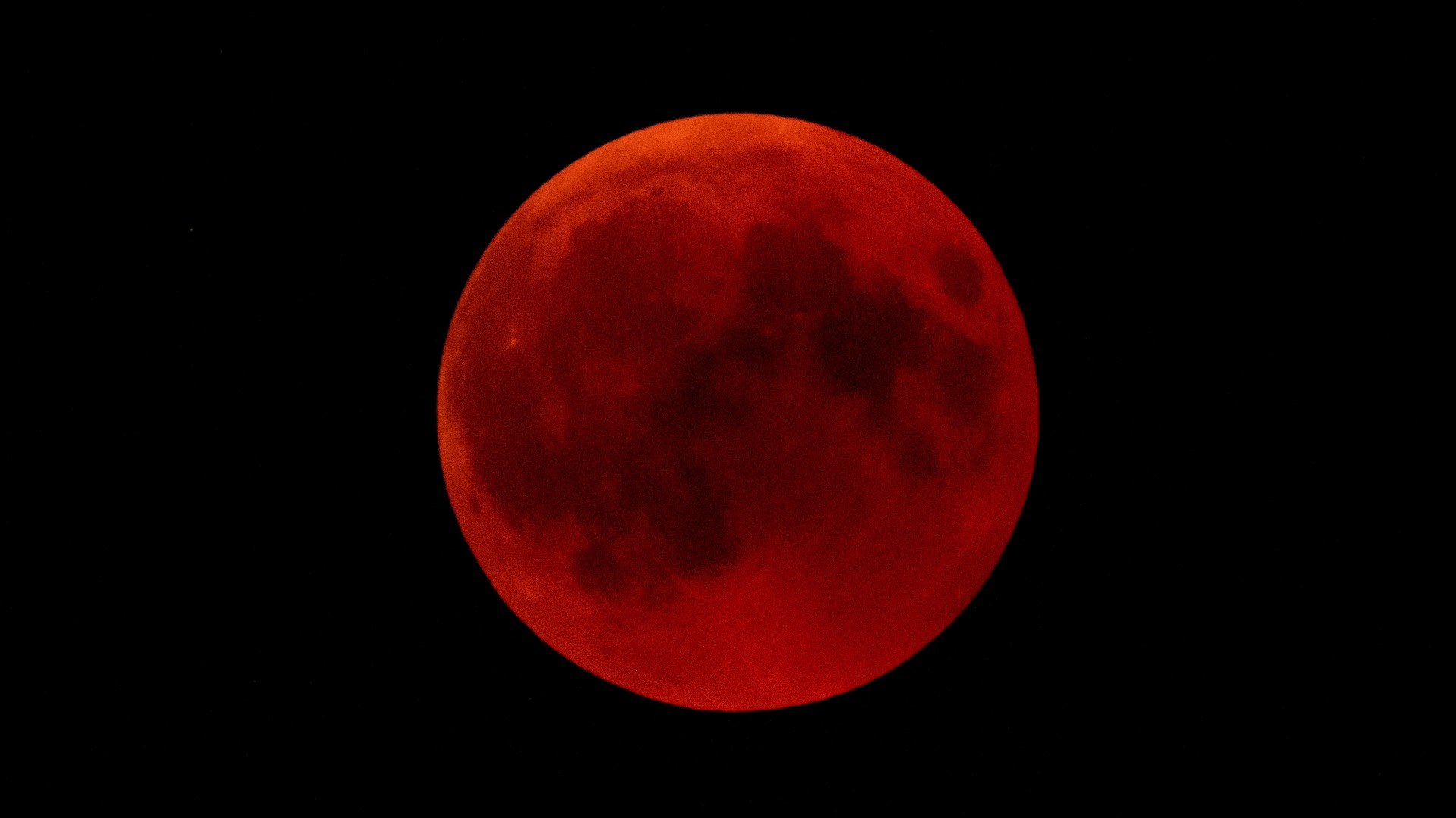 a blood red moon in a black night sky