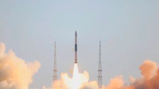 a black and white rocket launches into a blue sky.