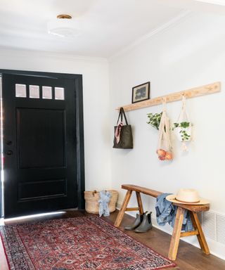 Entryway with black front door, Persian rug, wooden shelf and bench