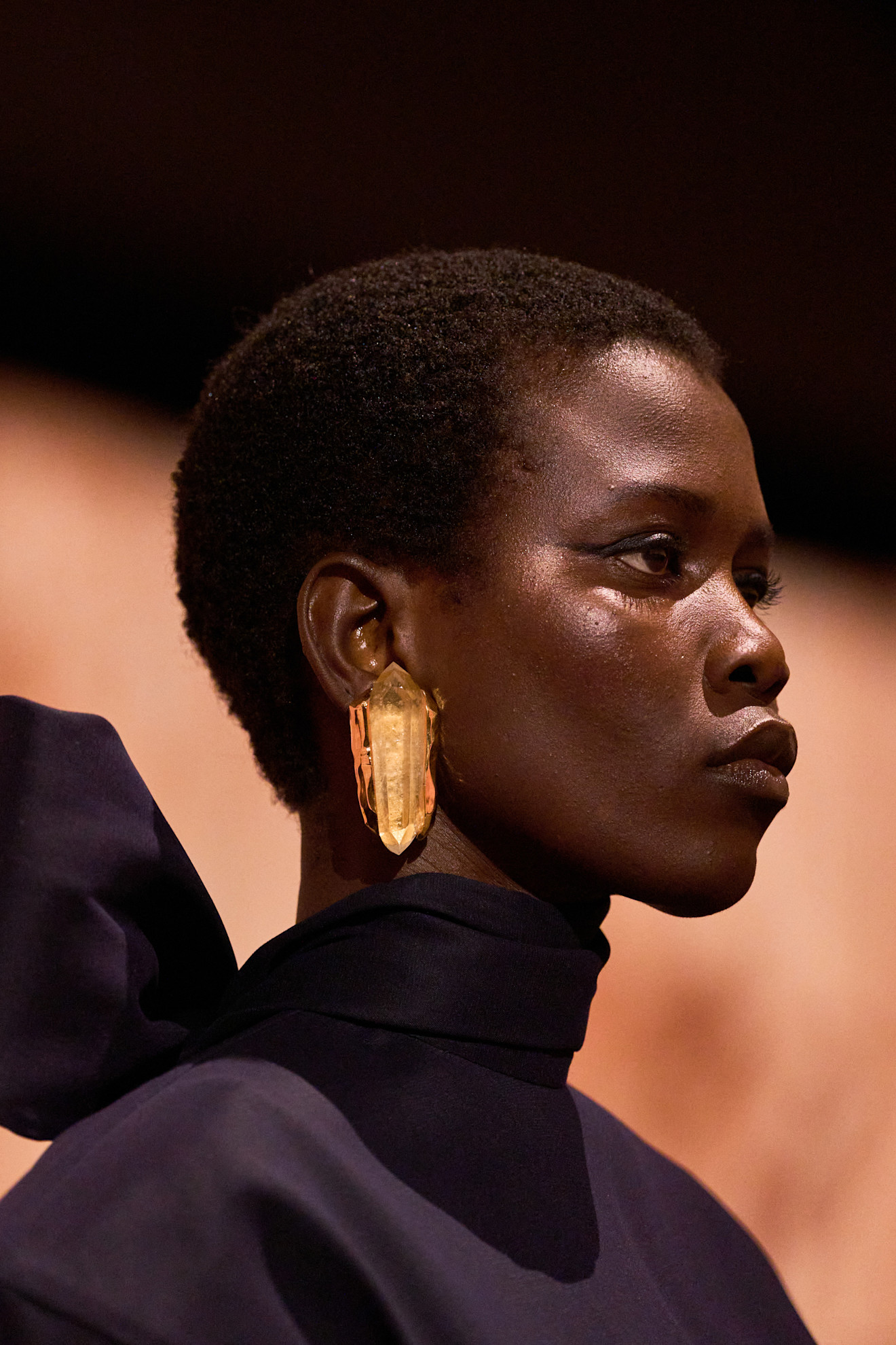 A Saint Laurent model wearing a yellow crystal earring and purple dress.
