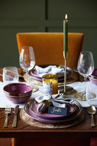autumnal fall table decor with turmeric coloured velvet chair, berry plates and bowls, green candle, glassware