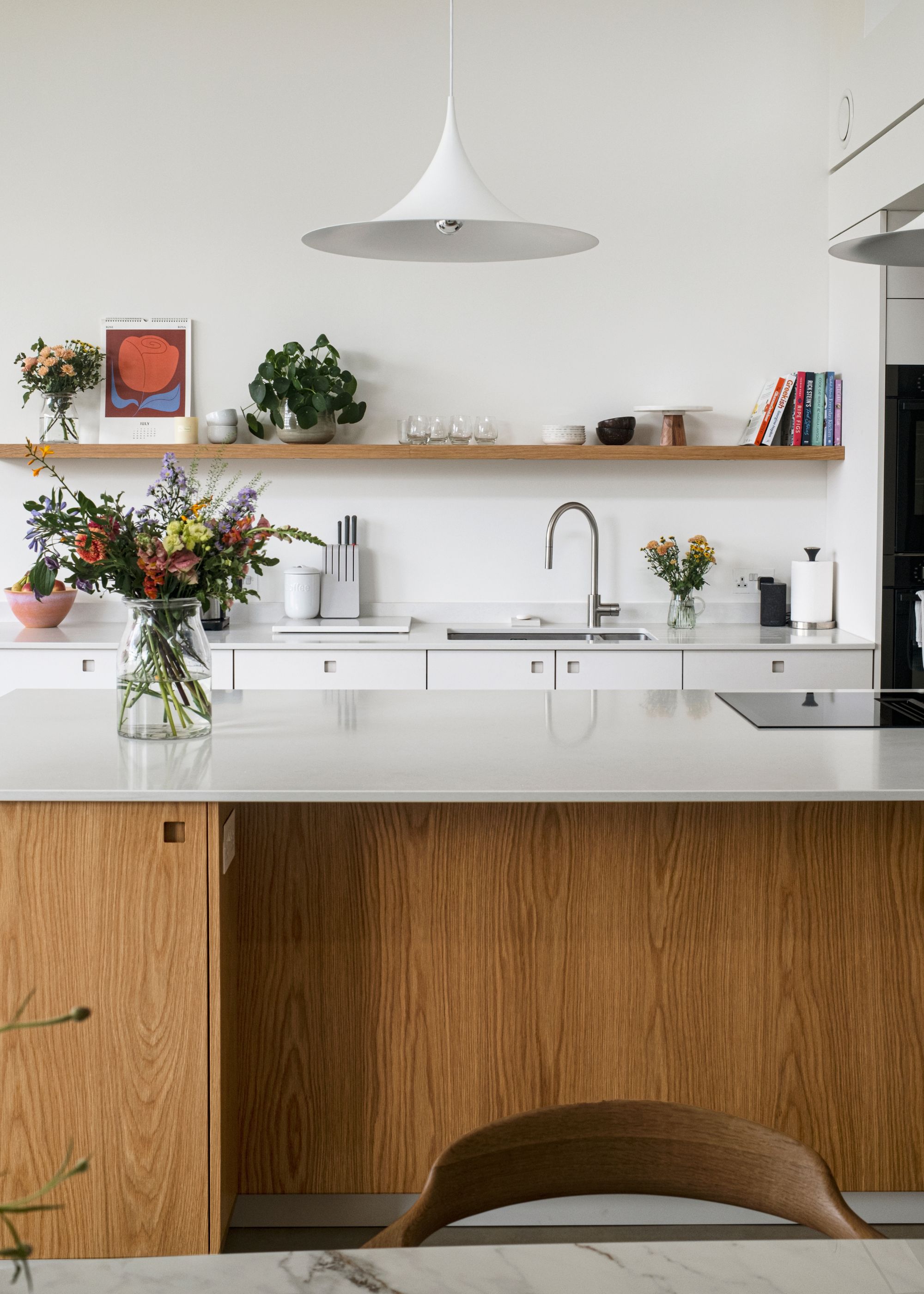 Modern kitchen with warm wood cabinets, white walls and sleek countertops.