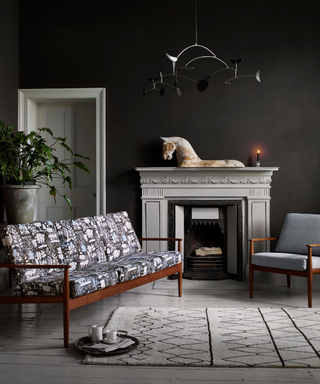 living room with black walls, white flooring and a black and white patterned mid century style sofa