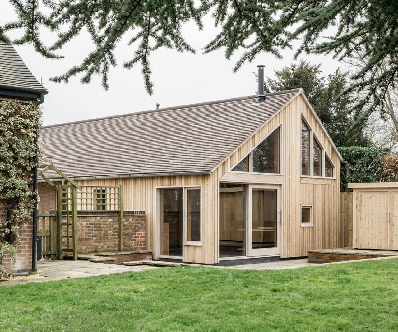 before and after images of garage block converted into an extended annexe with larch gladding and pitched roof