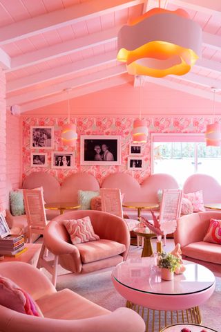 A pink-shaded motel features whimsically shaped, soft furniture and wooden ceilings also drenched in rose-hued paint.