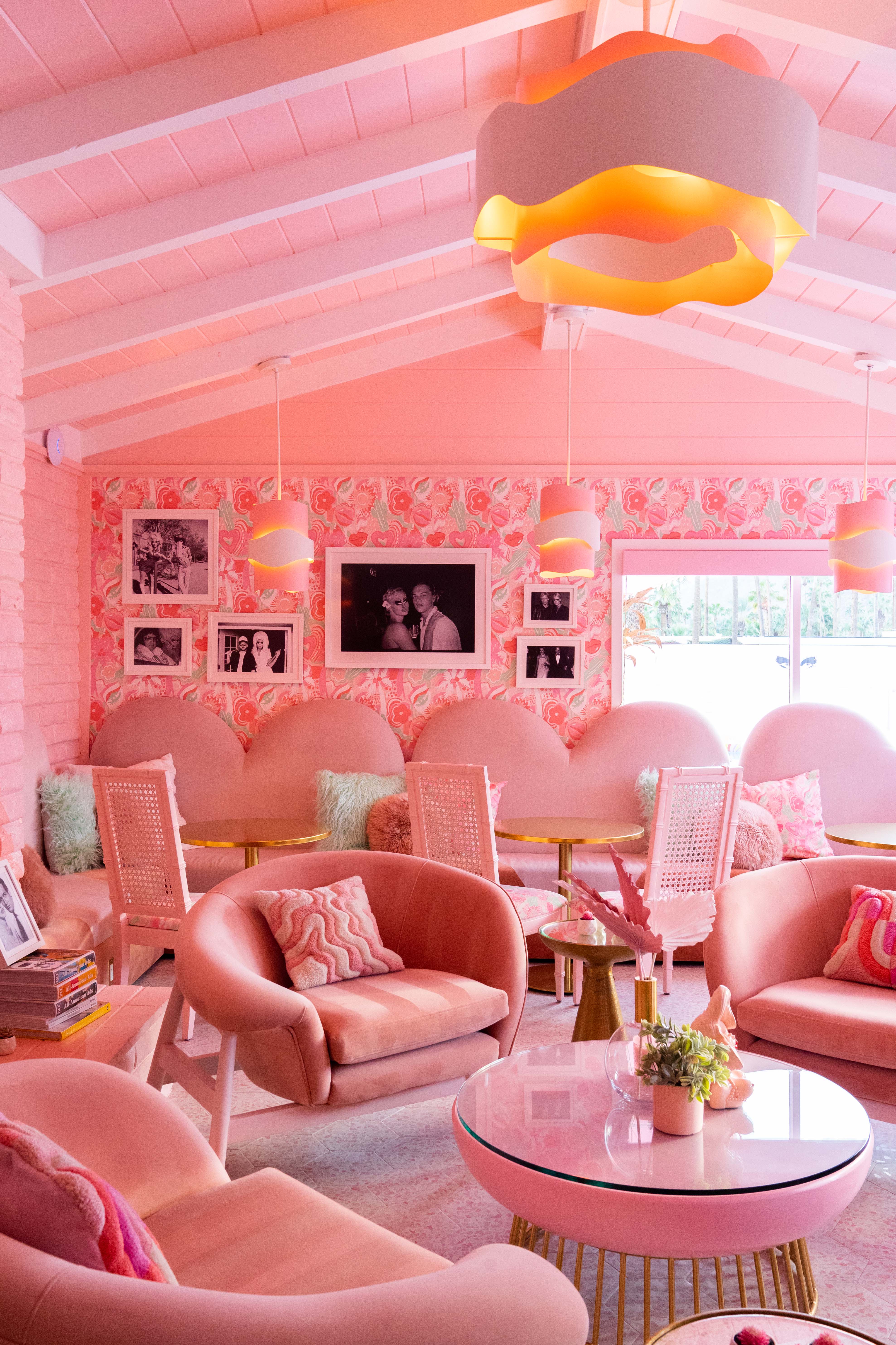 A pink-shaded motel features whimsically shaped, soft furniture and wooden ceilings also drenched in rose-hued paint.