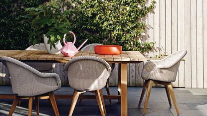 Outdoor dining area with stone floor, Teak dining table and Teak chairs with woven resin seats.