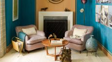 living room with pink accent chairs and blue walls