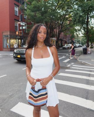 Sierra Mayhew wearing a white dress and A.L.C. crochet handbag