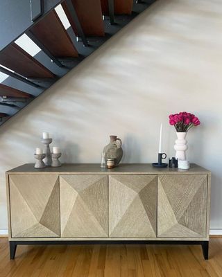 A gold console table with decor on it underneath a staircase